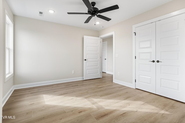 unfurnished bedroom featuring light hardwood / wood-style floors, ceiling fan, and a closet