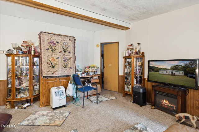 living room with wood walls, a textured ceiling, beamed ceiling, and light colored carpet