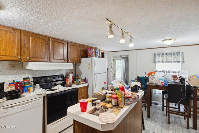 kitchen with white appliances, light hardwood / wood-style floors, a kitchen island, and a textured ceiling