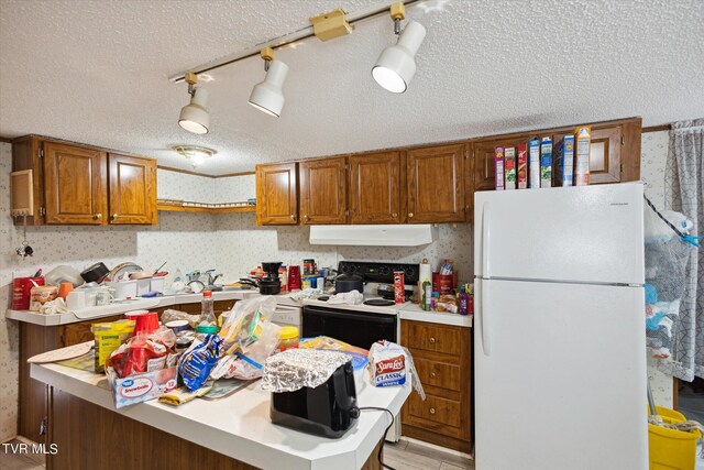 kitchen with light wood-type flooring, a textured ceiling, kitchen peninsula, white appliances, and exhaust hood