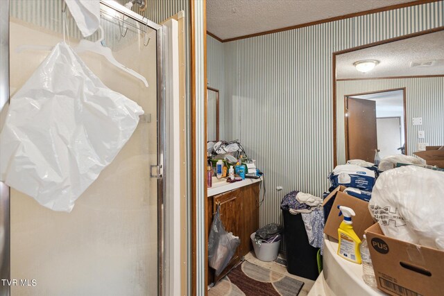 bathroom with walk in shower, a textured ceiling, and ornamental molding