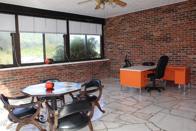 interior space with a textured ceiling, ceiling fan, and brick wall