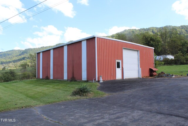 view of outdoor structure with a garage, a mountain view, and a yard