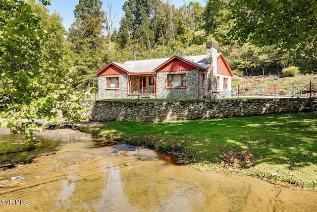 view of front facade featuring a water view and a front lawn