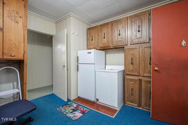 laundry area with wooden walls, dark colored carpet, and washer / dryer