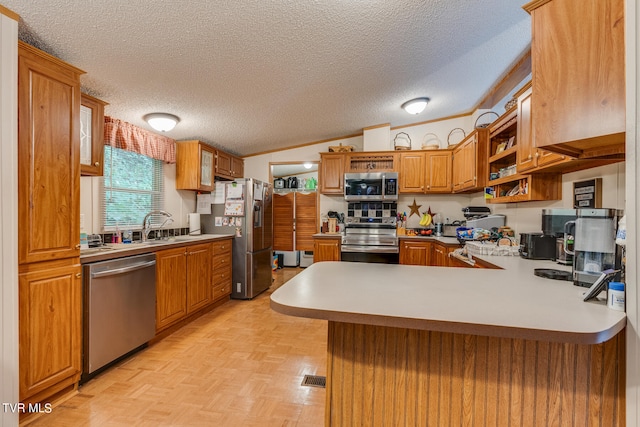 kitchen with a textured ceiling, vaulted ceiling, kitchen peninsula, stainless steel appliances, and light parquet floors