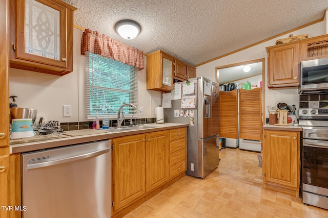 kitchen with appliances with stainless steel finishes, a textured ceiling, lofted ceiling, and sink