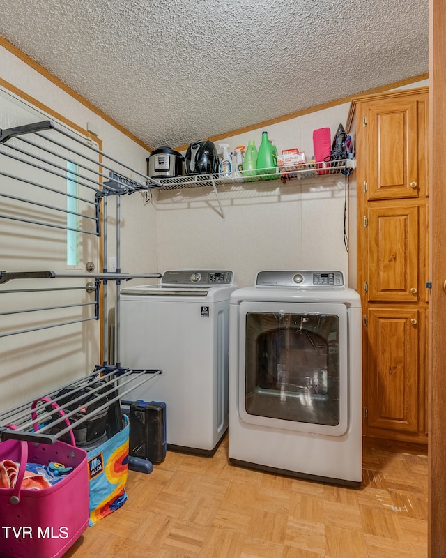 washroom featuring a textured ceiling, ornamental molding, light parquet floors, and washing machine and clothes dryer