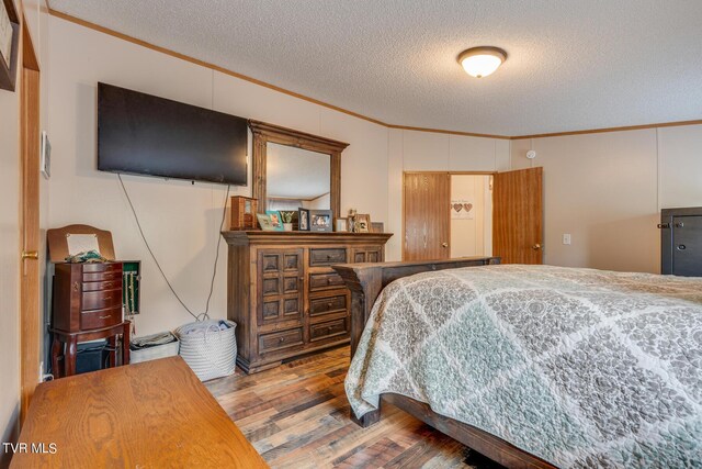 bedroom featuring a textured ceiling, ornamental molding, and hardwood / wood-style floors