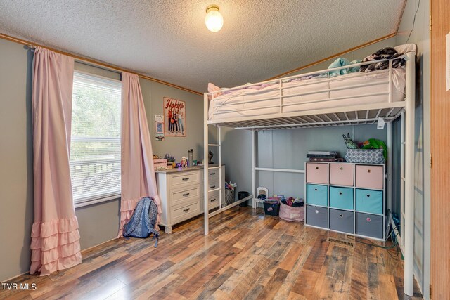 bedroom featuring a textured ceiling, crown molding, and dark wood-type flooring