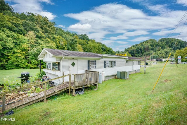 rear view of property with a deck, a yard, and central air condition unit