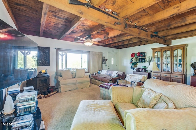 carpeted living room with ceiling fan, beamed ceiling, wood ceiling, and a wood stove