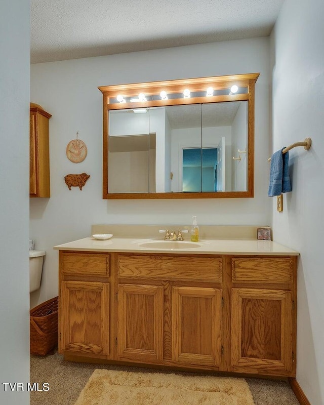 bathroom featuring vanity, toilet, and a textured ceiling