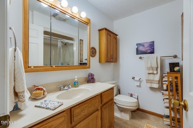 bathroom with vanity, a shower with shower door, toilet, and a textured ceiling