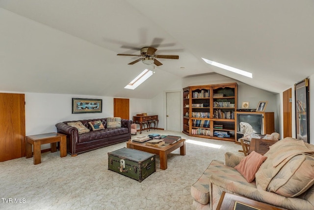 carpeted living room with ceiling fan and vaulted ceiling with skylight