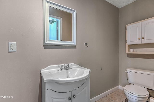 bathroom with tile patterned flooring, a textured ceiling, vanity, and toilet