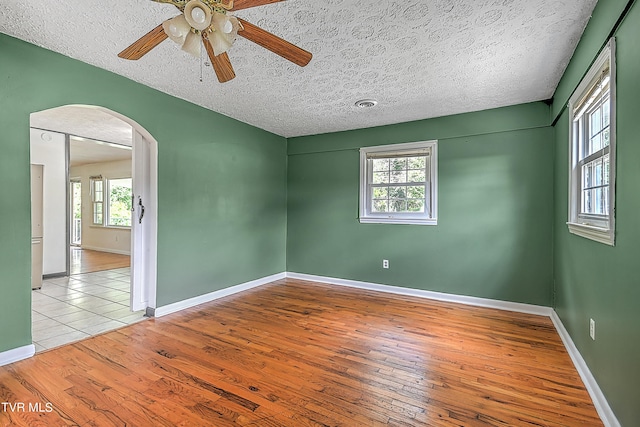 spare room with light wood-type flooring, a textured ceiling, and ceiling fan