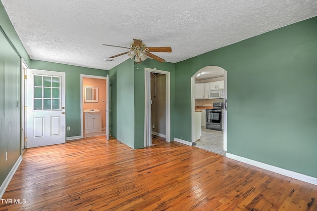 empty room featuring ceiling fan, a textured ceiling, and light wood-type flooring