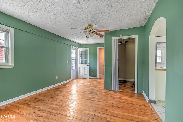 unfurnished bedroom featuring ceiling fan, a textured ceiling, light hardwood / wood-style flooring, and a closet