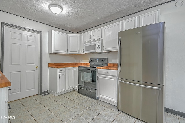 kitchen featuring stainless steel fridge, white cabinetry, butcher block counters, and electric range