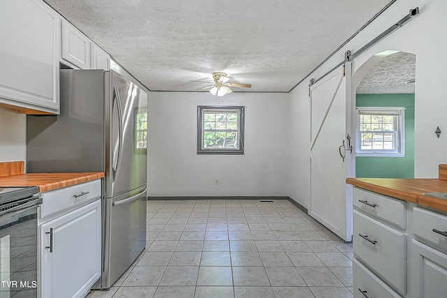 kitchen featuring white cabinets, butcher block counters, a wealth of natural light, and ceiling fan