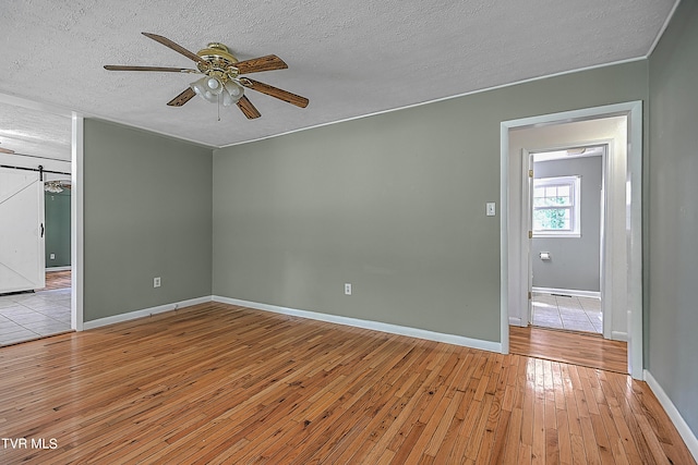 spare room featuring light hardwood / wood-style flooring, ceiling fan, and a textured ceiling