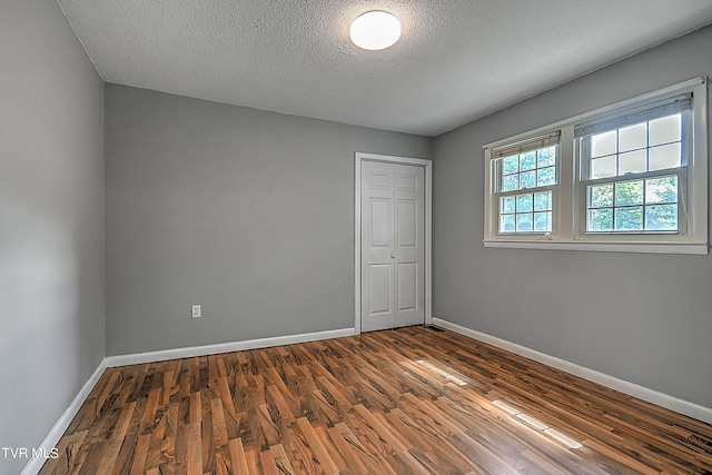 spare room featuring a textured ceiling and dark wood-type flooring