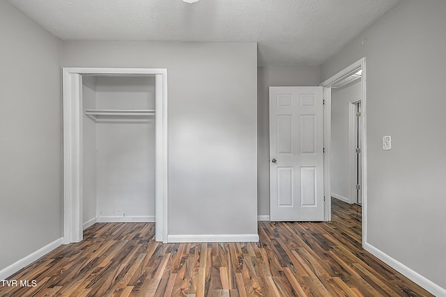 unfurnished bedroom with a textured ceiling, a closet, and dark wood-type flooring