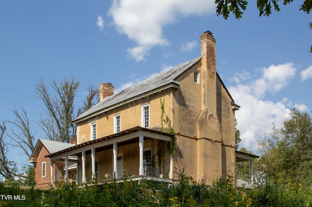 2666 Main St, Surgoinsville, TN 37873 - view of side of home featuring stucco siding, covered porch, and a chimney