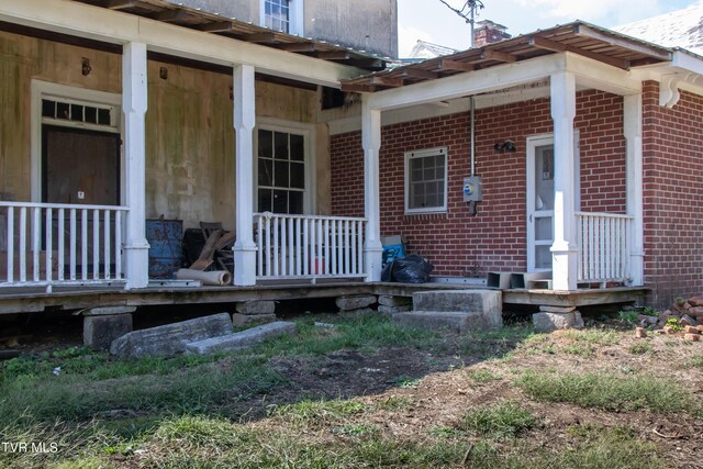 2666 Main St, Surgoinsville, TN 37873 - view of exterior entry featuring a chimney, a porch, and brick siding