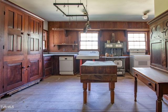 kitchen with light hardwood / wood-style flooring, wood walls, white appliances, and a wealth of natural light