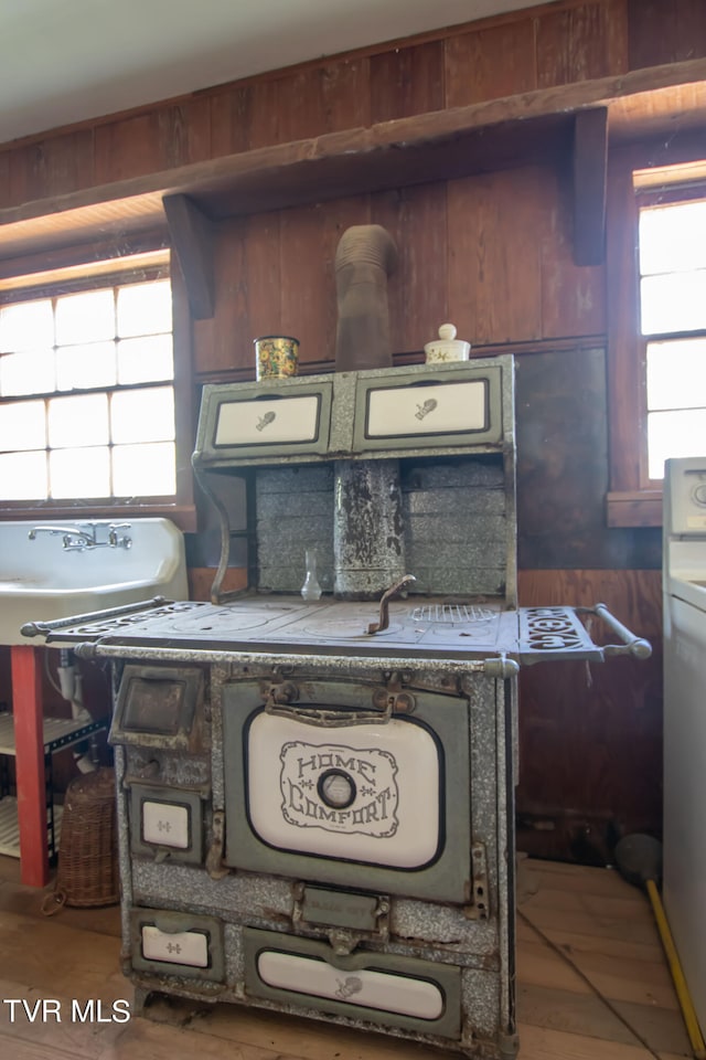 kitchen with hardwood / wood-style flooring, wooden walls, and washing machine and dryer