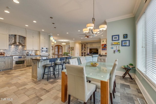 dining area with ornamental molding, an inviting chandelier, and a wealth of natural light