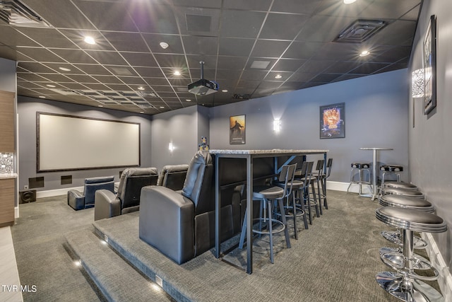 carpeted home theater with a paneled ceiling and indoor bar