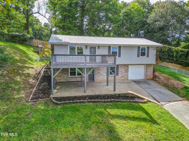 view of property with a garage, a wooden deck, a front lawn, and a patio area