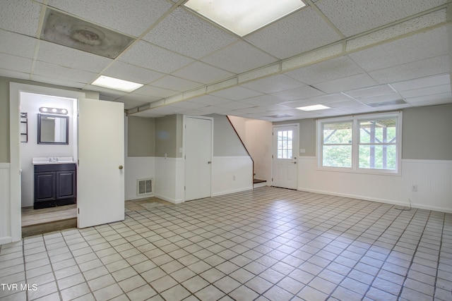 tiled empty room featuring a paneled ceiling