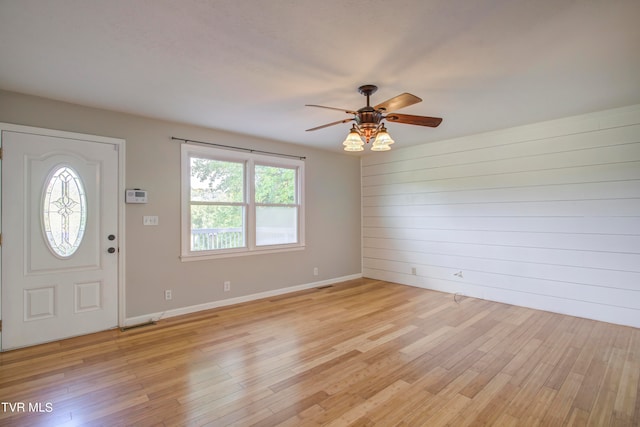 foyer entrance with ceiling fan, light hardwood / wood-style flooring, and wood walls