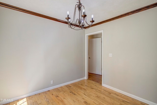 unfurnished room with an inviting chandelier, light wood-type flooring, and crown molding