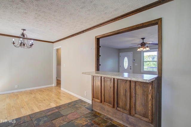 kitchen with dark wood-type flooring, ceiling fan with notable chandelier, pendant lighting, a textured ceiling, and ornamental molding