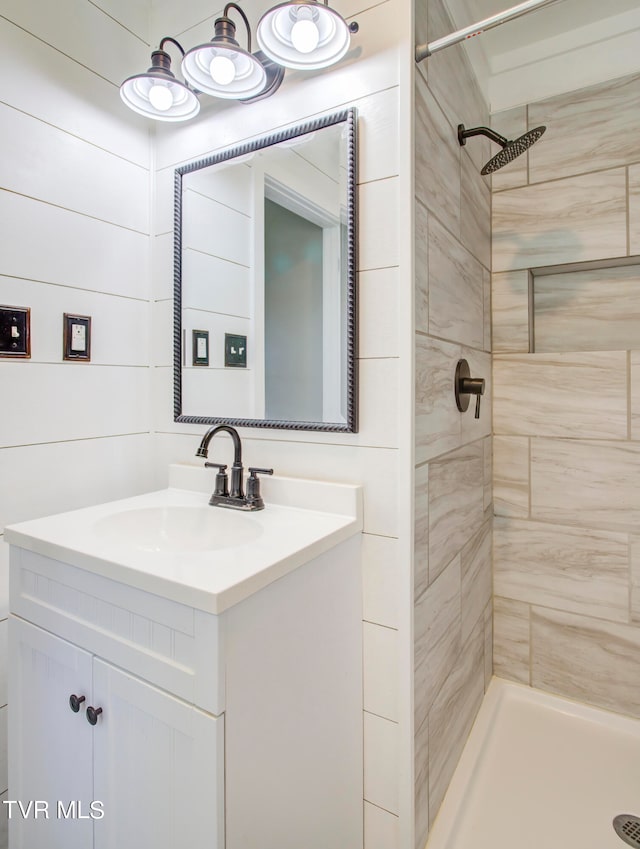 bathroom with a tile shower and vanity