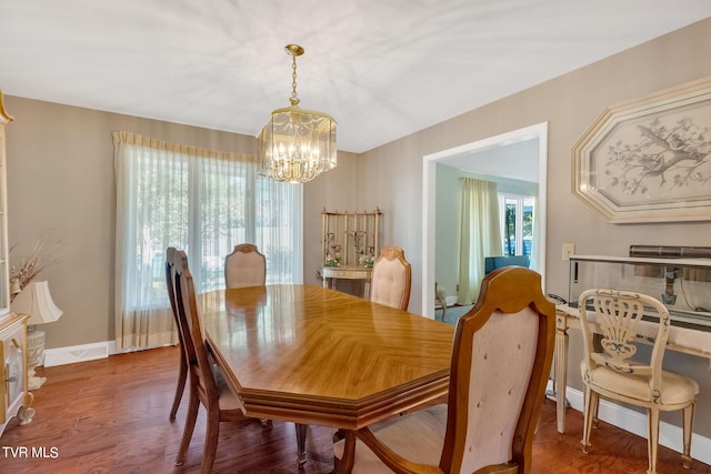 dining area with wood-type flooring and a notable chandelier