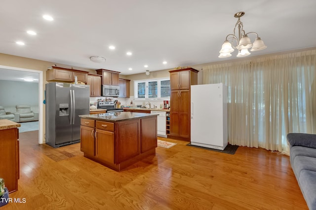 kitchen with stainless steel appliances, hanging light fixtures, light hardwood / wood-style floors, and a center island