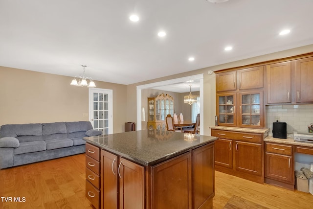 kitchen featuring pendant lighting, backsplash, a center island, an inviting chandelier, and light wood-type flooring