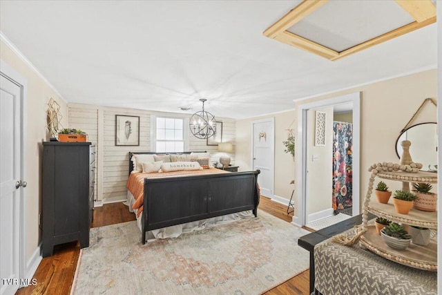 bedroom with wood-type flooring, a notable chandelier, and crown molding