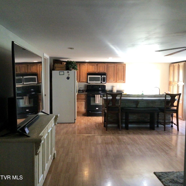 kitchen featuring black electric range, wood-type flooring, white refrigerator, and ceiling fan