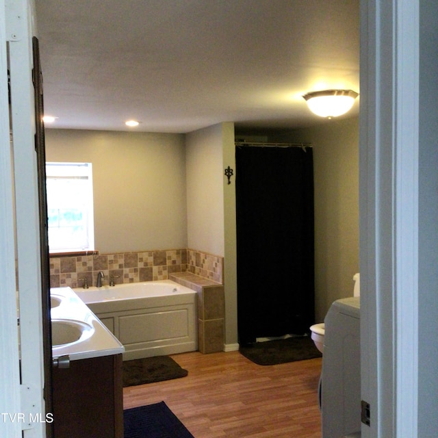 bathroom with vanity, toilet, wood-type flooring, and a tub to relax in