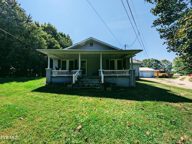 bungalow featuring a front lawn, covered porch, an outbuilding, and a garage