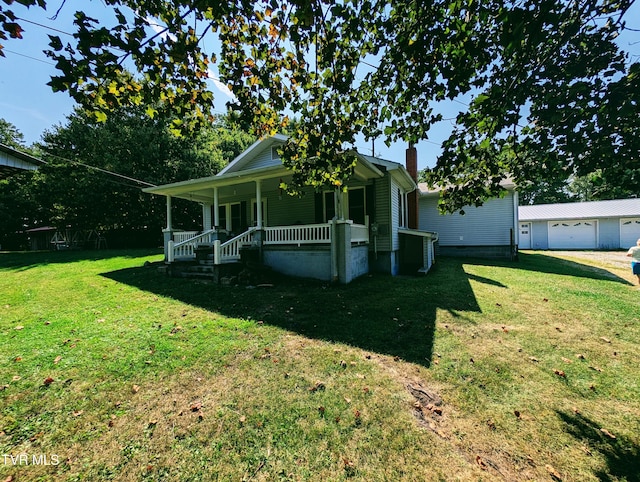 view of front facade featuring a front yard, a garage, an outdoor structure, and covered porch