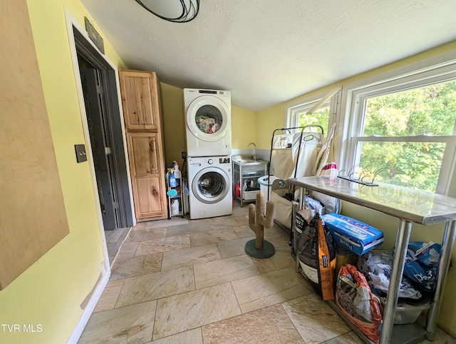 laundry room with a textured ceiling, sink, and stacked washing maching and dryer