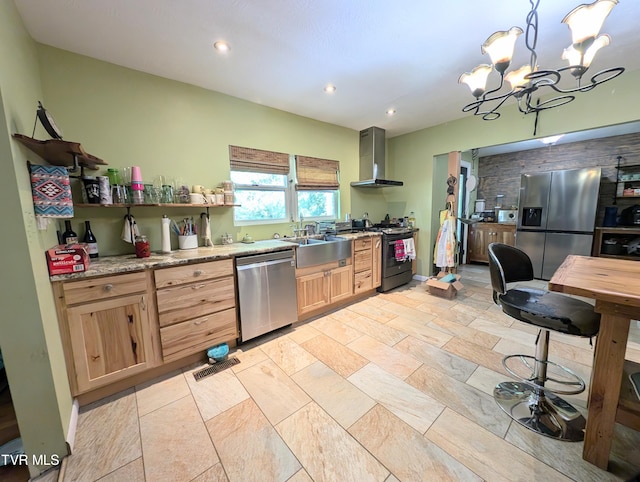 kitchen featuring sink, decorative light fixtures, wall chimney range hood, appliances with stainless steel finishes, and an inviting chandelier